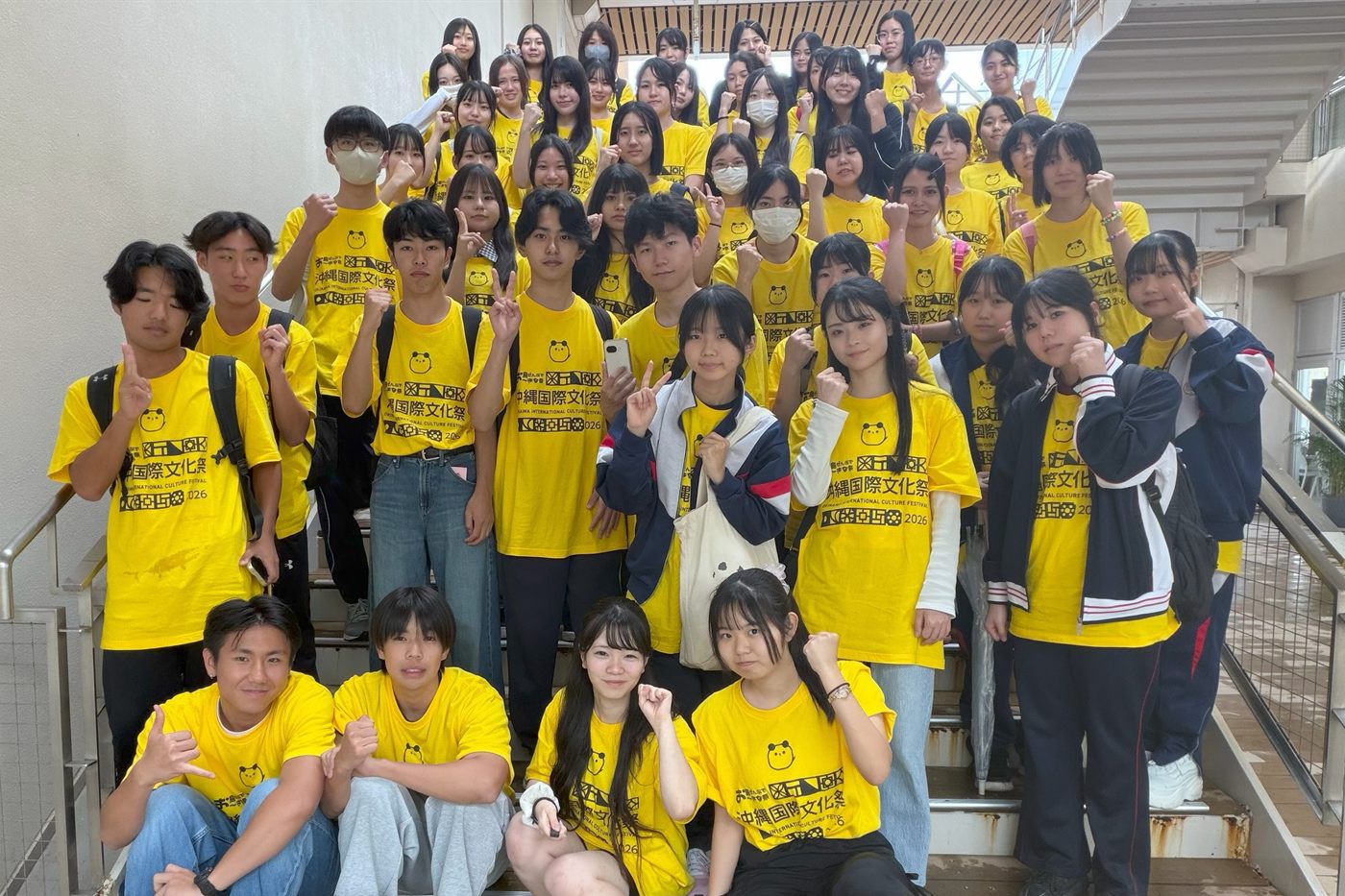 沖縄国際文化祭2026の黄色いスタッフTシャツを着た学生運営メンバーの集合写真